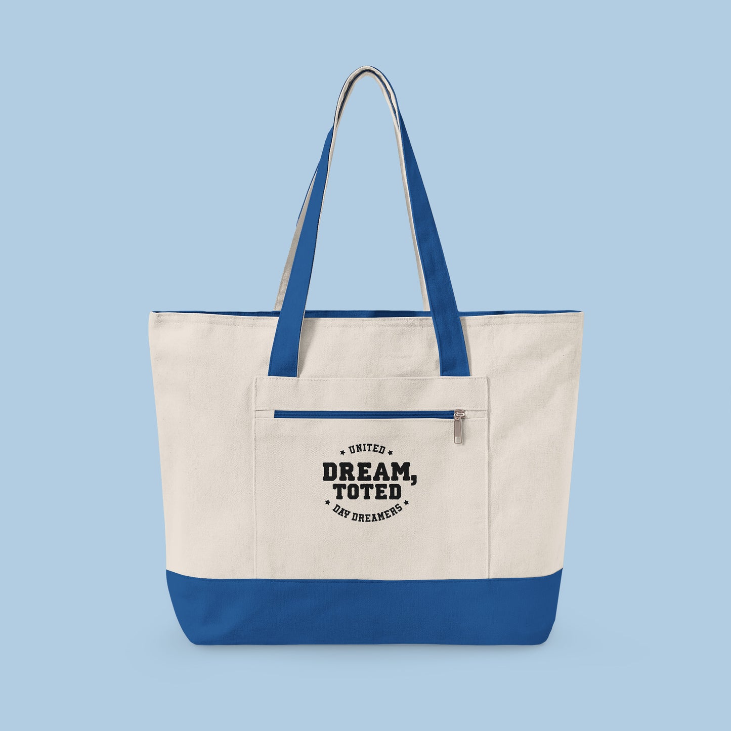 Beige tote bag with blue accents and text that reads, Dream, Toted. United Day Dreamers on a light blue background