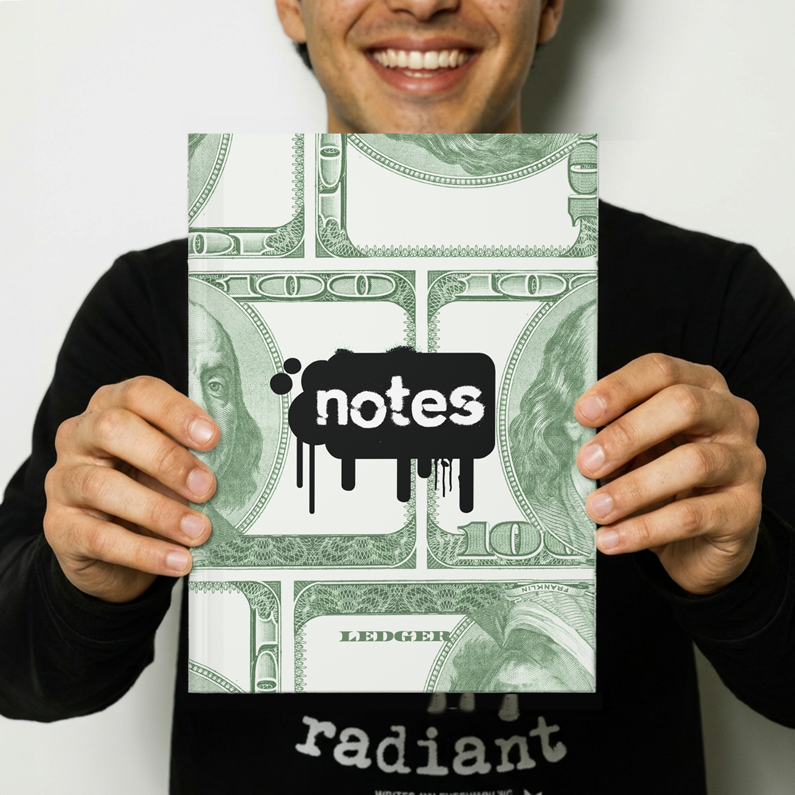 Man holding a notebook with 100 dollar bill design and 'notes' text.