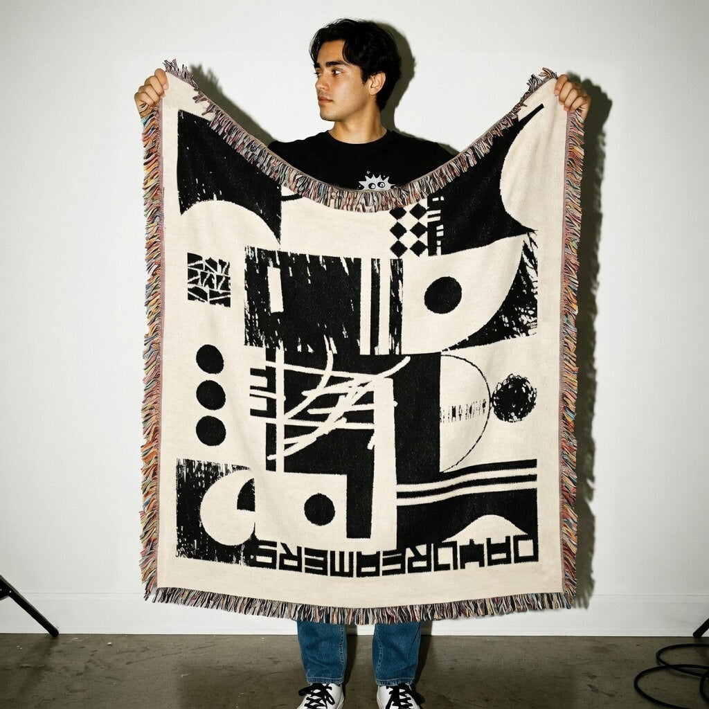 Man holding a large abstract tapestry with geometric patterns on a plain background