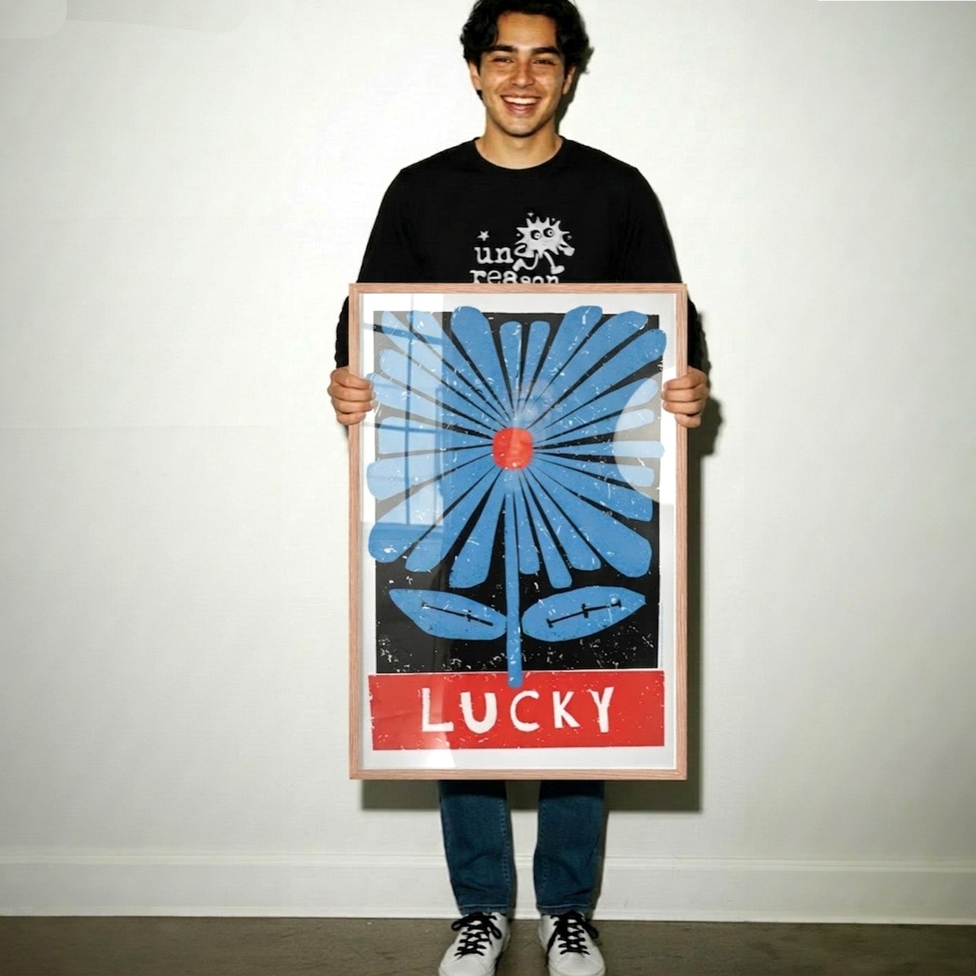 Person holding a large framed artwork with a blue flower design and 'LUCKY' text.